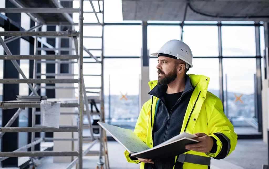 Ingeniero civil estudiando para el examen PMP 2026 frente a planos de obra